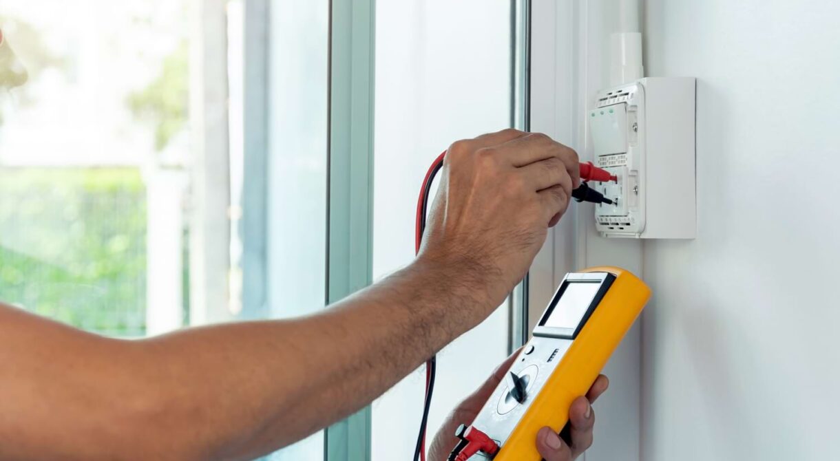 Un électricien mesurant la tension d’une installation électrique lors d’un diagnostic.